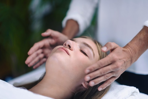 Reiki therapist holding hands on both sides of patient head and transfer energy beautiful and peaceful teenage girl lying with her eyes closed alternative therapy concept