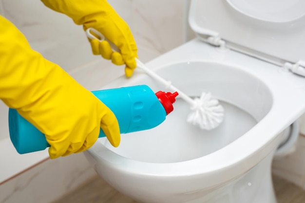 Reiniging en desinfectie van toiletten Reiniger in gele rubberen handschoenen reinigt het toilet met een borstel