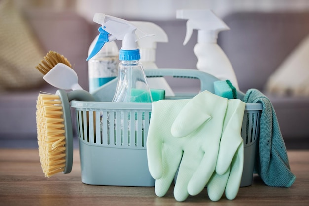 Reinigingsproducten en mand op tafel in de huiskamer voor de voorjaarsschoonmaak Hygiënische schoonmaakbenodigdheden en huishoudelijke apparatuur voor het desinfecteren, ontsmetten of verwijderen van ziektekiemen, bacteriën of stof