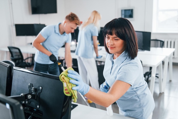 Reinigt monitor Groep werknemers maken samen modern kantoor overdag schoon