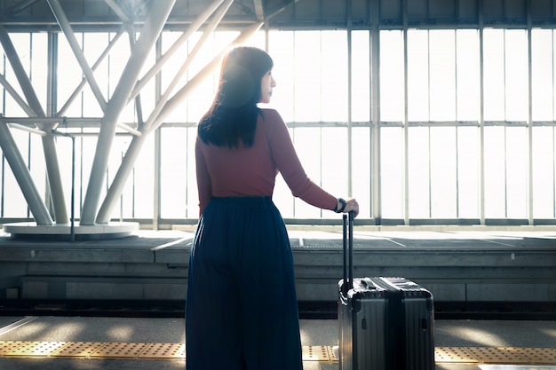 Reis Concept. Jonge vrouw te wachten met koffer op het platform op het treinstation