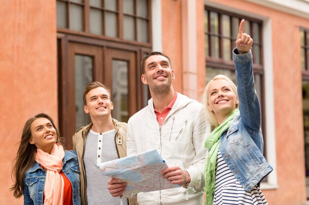 reis-, vakantie- en vriendschapsconcept - groep lachende vrienden met stadsplattegrond die de stad verkent