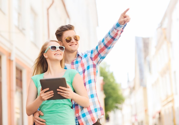 reis, vakantie, technologie en vriendschapsconcept - glimlachend paar met de computer van tabletpc in stad