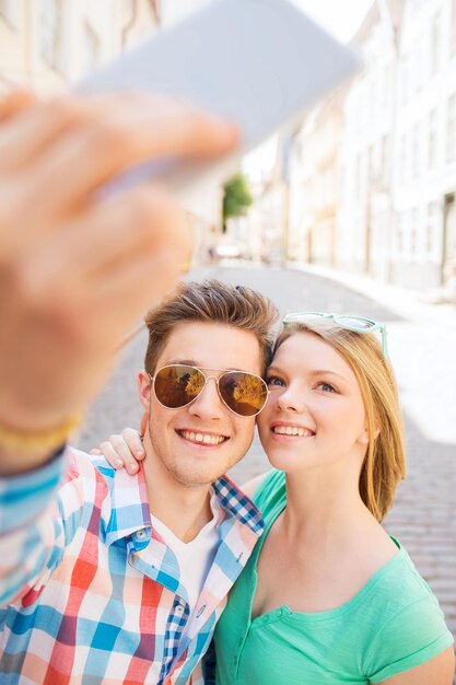 reis, vakantie, technologie en vriendschapsconcept - glimlachend paar met smartphone in stad