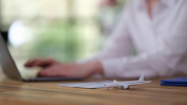 Reisbureau werkt op laptop aan tafel met speelgoedvliegtuig