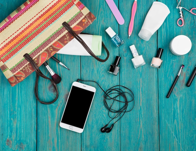 Reisconcept zomer vrouwen set met strozak smartphone met koptelefoon cosmetica make-up en essentials