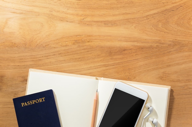 reisplanning concept met paspoort, mobiel, oortelefoon, potlood en open blanco papier nee