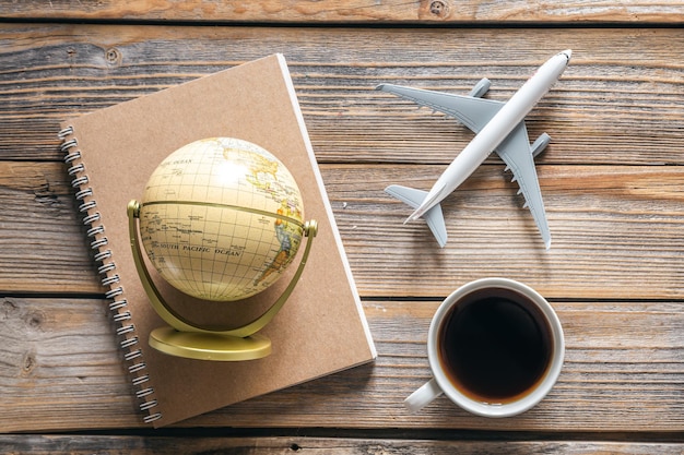 Foto reissamenstelling met kladblok globe vliegtuigmodel en koffiekopje bovenaanzicht