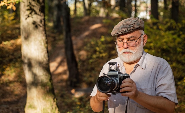 Reisshoot Fotograaf in het bos Lifestyle met herfst natuur retro fotoapparatuur Rijpe man met baard foto's groen landschap Fotograaf Nemen van foto Landschapsfotografie