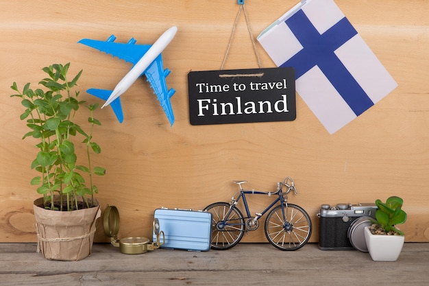 Reistijd concept schoolbord met tekst tijd om te reizen Finland vlag van het Finse vliegtuigmodel kleine fiets en koffer kompas
