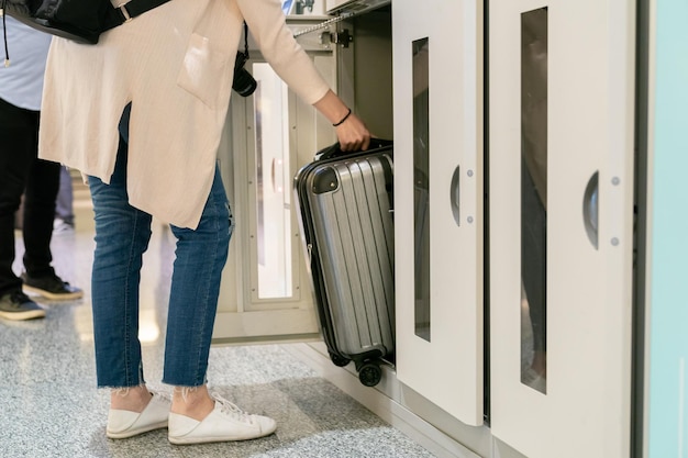 reisvrouw die de bagage in de kluis stopt. klaar voor korte tijd bezichtigingen. stijlvol en elegant dragen.