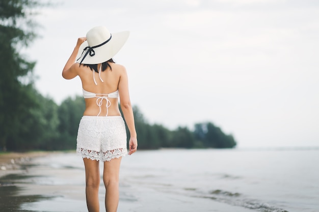 Reisvrouw die op strand in zonsondergang lopen