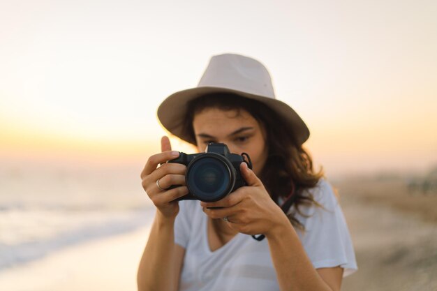 Reizen en fotografie Jonge vrouw met een camera wordt gefotografeerd op het zeestrand