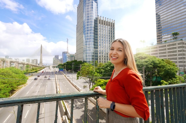 Reizen in Sao Paulo, Brazilië Portret van mooi lachend meisje met Sao Paulo stadsgezicht en Ponte Estaiada brug op de achtergrond Sao Paulo, Brazilië