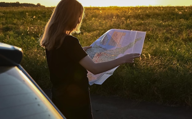 Reizen met de auto Roadtrip toeristenmeisje met een kaart staat in de buurt van de auto