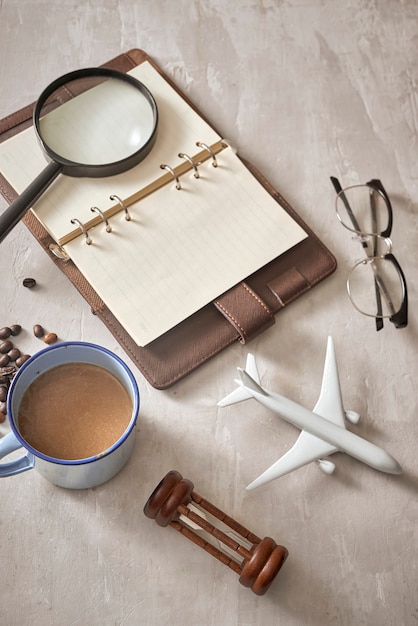 Reizen planning concept achtergrond. Accessoires voor reizigers; Vergrootglas, zonnebril, vliegtuig en notebook op houten tafel, bovenaanzicht en kopieerruimte copy