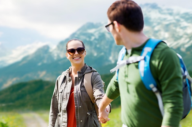 reizen, toerisme en mensen concept - gelukkig stel met rugzakken hand in hand over de achtergrond van de alpenbergen