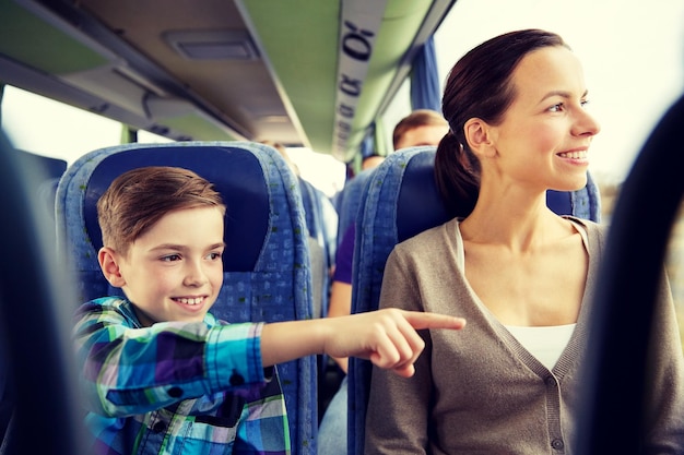 reizen, toerisme, familie, technologie en mensenconcept - gelukkige moeder en zoon rijden in reisbus