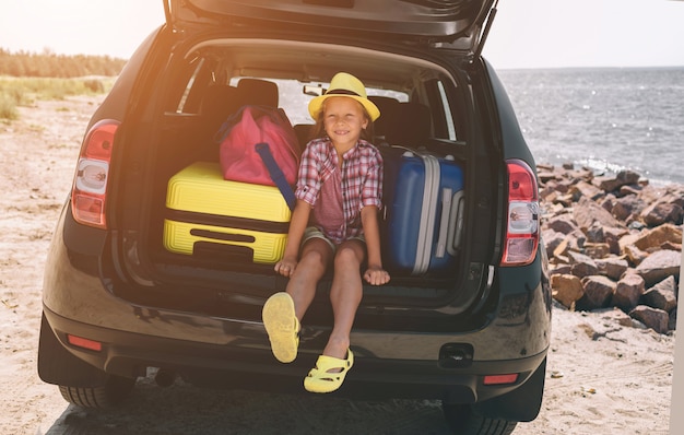 Reizen, toerisme - Meisje met tassen klaar voor de reis voor zomervakantie. Kind gaat op avontuur. Auto reizen concept