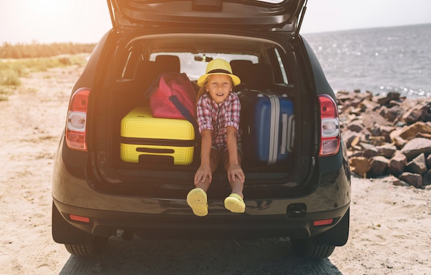 Reizen, toerisme - Meisje met tassen klaar voor de reis voor zomervakantie. Kind gaat op avontuur. Auto reizen concept