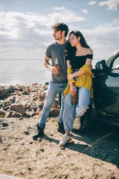 Reizen, toerisme - Picknick aan het water. Echtpaar gaat op avontuur. Auto reizen concept. Man en vrouw drinken bier.