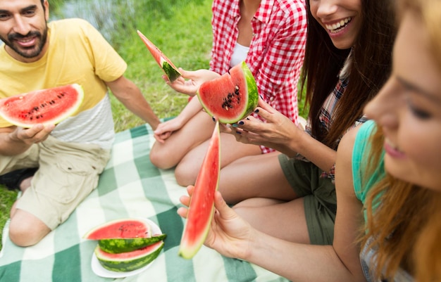 Foto reizen, toerisme, wandeling, picknick en mensenconcept - close-up van gelukkige vrienden met tent die watermeloen eten op de camping