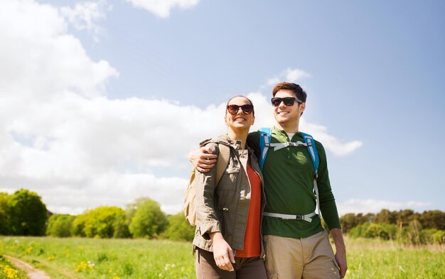 reizen, wandelen, backpacken, toerisme en mensenconcept - gelukkig stel met rugzakken knuffelen en buiten wandelen