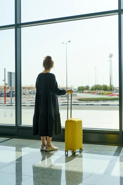 Reizend meisje met een koffer op de luchthaven Vakantievliegtuigen vluchten reizen concept