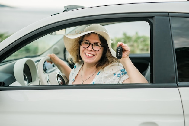 Reizende vrouw die de sleutels van een nieuwe auto vasthoudt en glimlacht naar camerabezit en aankoop autoconcept