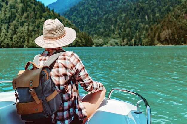 Reizige vrouw met rugzak geniet van het uitzicht op turquoise meer en bergen zittend op paddleboot