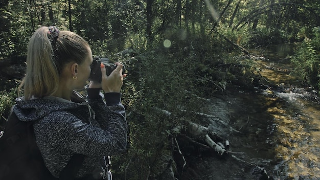 Foto reiziger die schilderachtig uitzicht in bosrivier fotografeert houten brug omgevallen boom een blanke vrouw die mooie magische blik schiet meisje neemt foto op camera