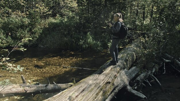 Reiziger die schilderachtig uitzicht in bosrivier fotografeert Houten brug omgevallen boom Een blanke vrouw die mooie magische blik schiet Meisje neemt foto op camera