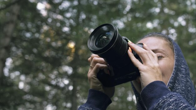 Reiziger die schilderachtig uitzicht in het bos fotografeert Een blanke vrouw die een close-up blik schiet Meisje neemt foto video op dslr spiegelloze camera Professionele fotograaf reizen met rugzak Buiten