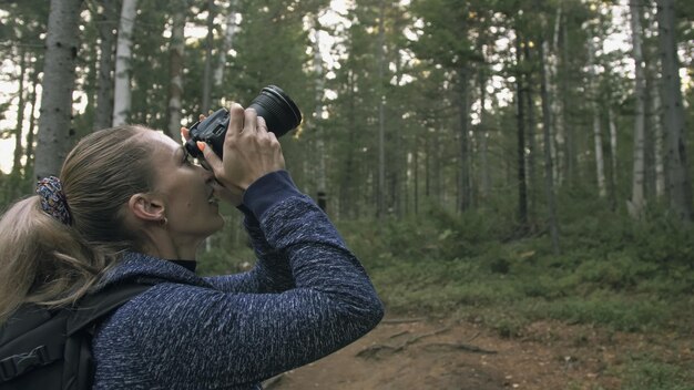 Reiziger die schilderachtig uitzicht in het bos fotografeert Een blanke vrouw die mooie magische blik schiet Meisje neemt foto video op dslr spiegelloze camera Professionele fotograaf reizen met rugzak Buiten