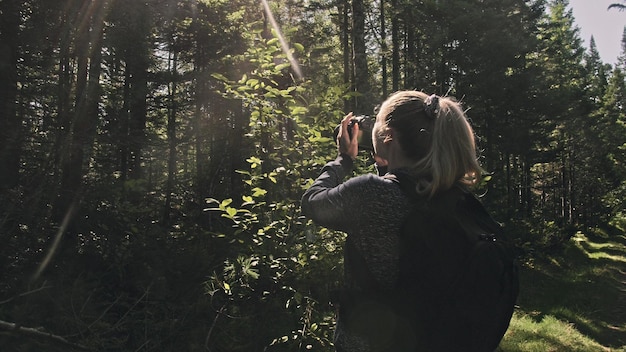 Reiziger die schilderachtig uitzicht in het bos fotografeert Een blanke vrouw die mooie magische blik schiet Meisje neemt foto video op dslr spiegelloze camera Professionele fotograaf reizen met rugzak Buiten