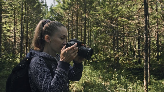 Foto reiziger die schilderachtig uitzicht in het bos fotografeert een blanke vrouw die mooie magische blik schiet meisje neemt foto video op dslr spiegelloze camera professionele fotograaf reizen met rugzak buiten