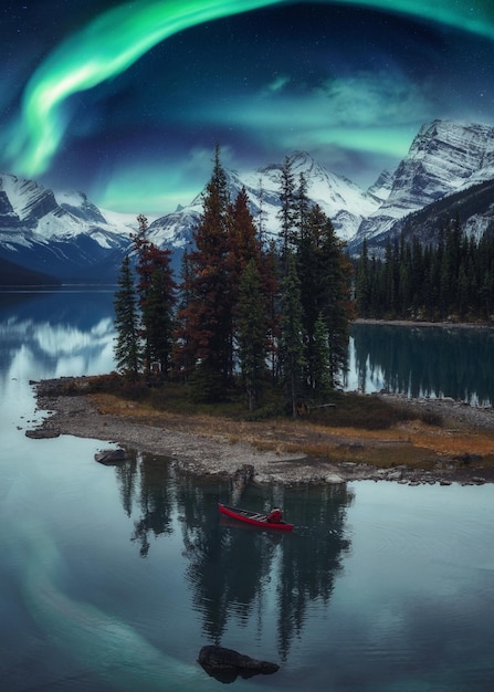 Reiziger man kanoën op Spirit Island met aurora borealis over rotsachtige bergen in de nacht in Jasper National Park Alberta Canada