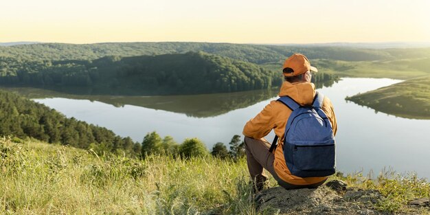 Reiziger man kijkt naar het bergmeer bij zonsondergang. Reiziger Man ontspannende meditatie met sereen uitzicht zomer landschap. Banier.