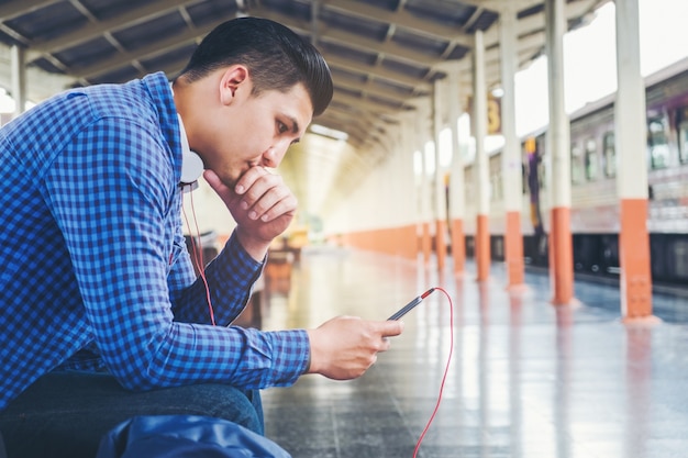 Reiziger Man met behulp van tablet en telefoon wachten op de trein op het station