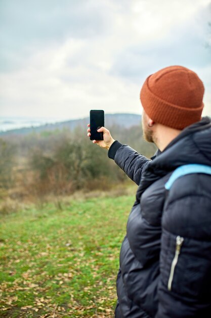 Reiziger man met rugzak maakt foto's of selfie op een smartphone, zijn telefoon met rivier en bergen Lifestyle.