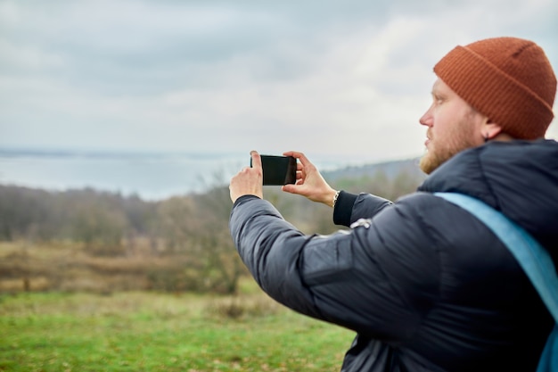 Reiziger man met rugzak maakt foto's of selfie op een smartphone