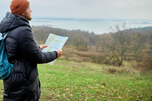 Reiziger man met rugzak met kaart in de hand poseren op bergen rivier van de natuur, reisconcept, vakanties en Lifestyle wandelconcept