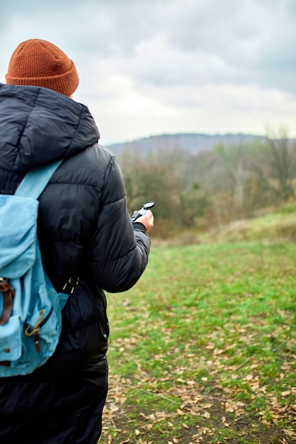 Reiziger man met rugzak met kompas in de hand op een muur van bergen rivier van de natuur, reisconcept, kampeertrip, gps, oriëntatieloop, navigator