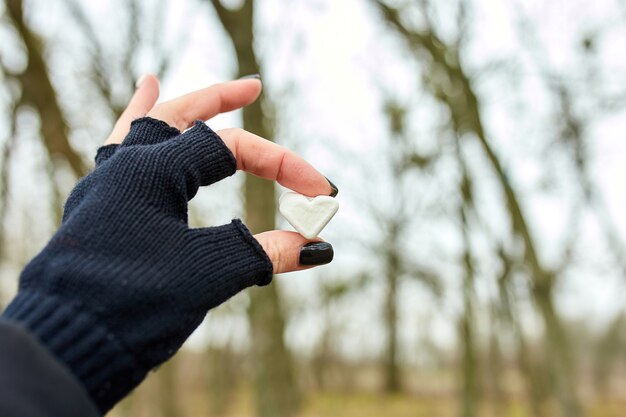 Reiziger meisje in zwarte handschoenen houdt in de hand marshmallow in gevormd hart