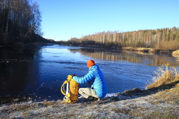 reiziger met een rugzak bij de rivier / toerist op een noordelijke wandeling, winterreis