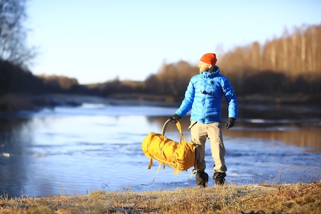 reiziger met een rugzak bij de rivier / toerist op een noordelijke wandeling, winterreis