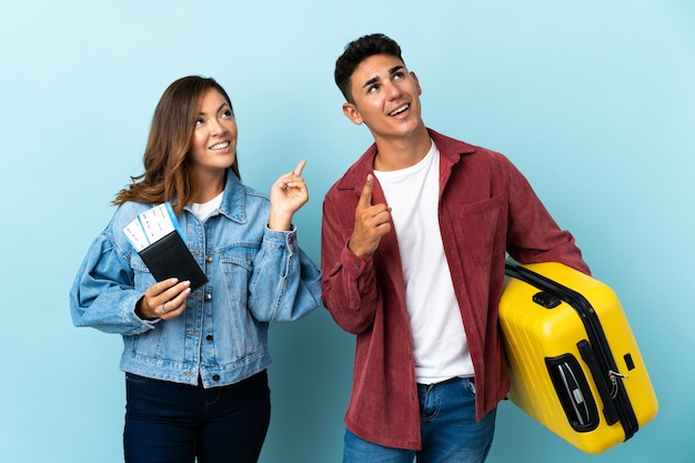 Reiziger paar met een koffer op blauw wijzend met de wijsvinger een geweldig idee