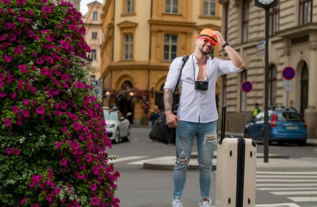 Reiziger toeristische man in casual kleding hoed met koffer man reiziger met reistas buiten portret