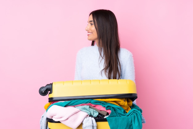 Reiziger vrouw met een koffer vol kleren op zoek naar de kant