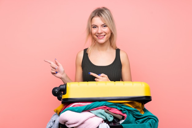 Reiziger vrouw met een koffer vol kleren wijzende vinger naar de kant